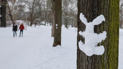 Ein Hase aus Schnee klebt an einem Baum. Zum Start der Osterferien ist es winterlich in Baden-Württemberg.