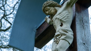 Eine Statue von Jesus hängt an einem Holzkreuz. An Karfreitag gedenken Christen seinem Leiden und Sterben, mit dem er laut dem christlichen Glauben die Sünden der Welt auf sich genommen hat.