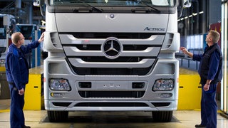 Mitarbeiter überprüfen in Wörth im Werk von Mercedes Benz einen Lastkraftwagen. 