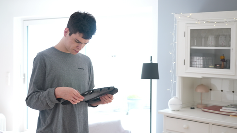 Elias steht im Raum und schaut auf sein Handy. Er ist eins von vielen Kindern mit Autismus, die Unterstützung brauchen.