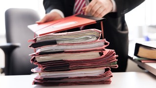 Ein Oberstaatsanwalt bindet einen Stapel Gerichtsakten (Symbolbild). Zur Jahreswende waren in Baden-Württemberg laut Statistik noch fast 84.000 Strafverfahren.