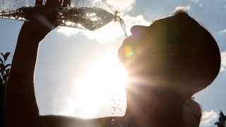 Hitze in Deutschland: Frau trinkt aus Wasserflasche. Droht ein Hitzesommer in BW durch ein "Super-El Niño"?