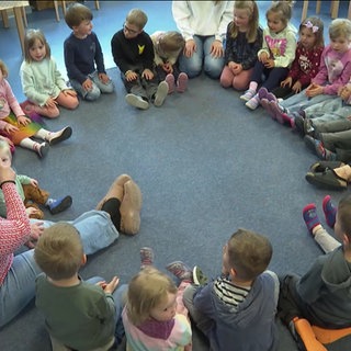 Kinder sitzen in einer Kita im Sitzkreis