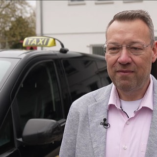 Dirk Holl vor einem E-Taxi