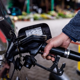 Eine Person hält die Zapfpistole einer Tankstelle in den Sutzen eines schwarzen Autos. Beim Carsharing müssen Fahrer zwar selbst tanken, die Kosten tragen aber die Anbieter.