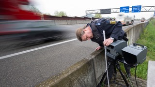 Eine mobile Geschwindigkeitsmessanlage der Autobahnpolizei Weinsberg wird am Rand der A6 von einem Polizeibeamten eingerichtet. Am Mittwoch ist in Baden-Württemberg Höhepunkt des "Blitzermarathons"