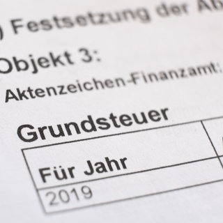 Ein Bescheid über die Grundsteuer liegt auf einem Schreibtisch. Baden-Württemberg ist bei der Neuregelung eigene Wege gegangen. Diese neuen Regeln werden nun jedoch vor dem Bundesfinanzhof behandelt. (Archivfoto)