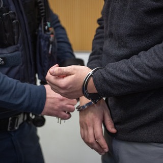 Ein Justizbediensteter löst im Landgericht die Handschellen eines Tatverdächtigen.