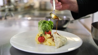 Ein Besuch im Restaurant kann teuer werden - dennoch stehen viele Gastronomen unter Druck (Symbolbild: Maultasche wird auf Teller angerichtet)