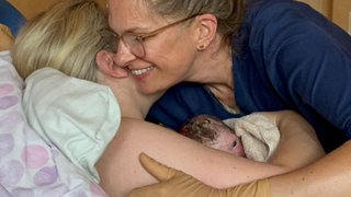 Hebamme Julia Schuhmacher umarmt eine Mutter, die gerade ihr Baby zur Welt gebracht hat