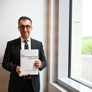 Der zukünftige Ministerpräsident Cem Özdemir (Grüne) hält den Koalitionsvertrag von Grünen und CDU in den Händen. 