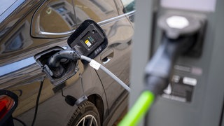 Ein Elektroauto hängt an einer Elektro-Ladesäule in der Innenstadt. Das Interesse an Elektroauto hat einer Forsa-Umfrage zufolge zugenommen. Höhere Energiepreise könnten einen Wandel bewirken.