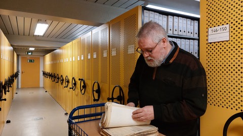 Archivar Hartmut Obst blättert durch Unterlagen im Staatsarchiv Ludwigsburg. Er hilft anderen bei der Recherche zur Familiengeschichte während der NS-Zeit.