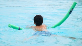 Ein Kind mit Poolnudel im Wasser: Manche Kinder können schon schwimmen, wenn sie in die Schule kommen. Andere haben große Angst.