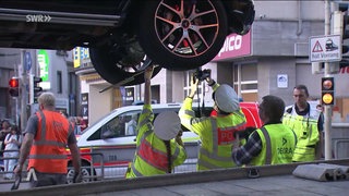 Auto auf einer hzebebühne und Polizizistinnen stehen darunter