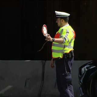 Ein Polizist winkt einen Autofahrer aus dem Verkehr