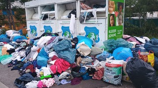 Mülltüten und weggeworfene Klamotten stapeln sich vor überfüllten Altkleidercontainern. Städte haben mit immer mehr wildem Müll zu kämpfen.
