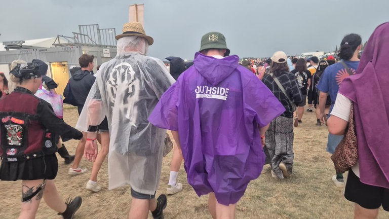 Menschen in Regenschutz verlassen das Festival-Gelände. Das Southside gehört zu den größten Rockfestivals Deutschlands.