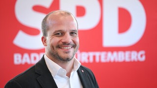 Jan-Peter Röderer steht beim Landesparteitag der SPD Baden-Württemberg in der Donauhalle vor einem Parteilogo. 