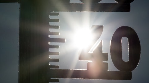 Die Sonne scheint hinter einem Thermometer mit der 40 Grad Anzeige: Hitze bricht neuen Rekord