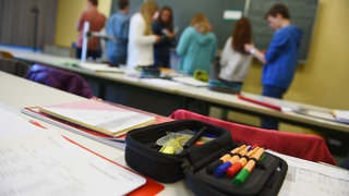 Schüler stehen in einem Gymnasium während des Unterrichts vor der Tafel und unterhalten sich über ihre Aufgabe (Archivbild).