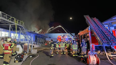 Mit Leitern und Teleskopen versucht die Feuerwehr den Brand in den Hallen des Großmarkts in Stuttgart-Wangen unter Kontrolle zu bringen.
