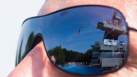 In einer Sonnenbrille spiegelt sich 04.07.2015 das Freibad "Sport Paradies" in Gelsenkirchen (Nordrhein-Westfalen). Gerade bei heißen Temperaturen sind Freibäder ein beliebtes Ziel.