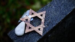 Ein abgebrochener Davidstern liegt während der Gedenkveranstaltung zum Volkstrauertag auf dem Jüdischen Friedhof Weißensee auf einem Grabstein.