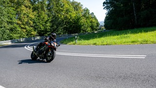 Ein Motorradfahrer fährt in einer Kurve im Hambach zwischen Ebern und Untermerzbach (Unterfranken). Das sonnige Wetter lockt zu Ausflügen.