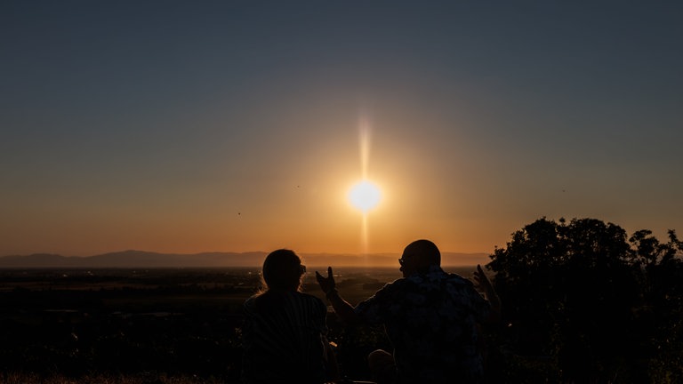 Menschen sitzen auf dem Batzenberg und sehen sich die partielle Sonnenfinsternis an. Wenn am Abend die partielle Sonnenfinsternis über Deutschland zu sehen ist, herrschen zu dieser Zeit fast überall auch optimale Wetterbedingungen, um sie zu beobachten, hieß es vom Deutschen Wetterdienst.
