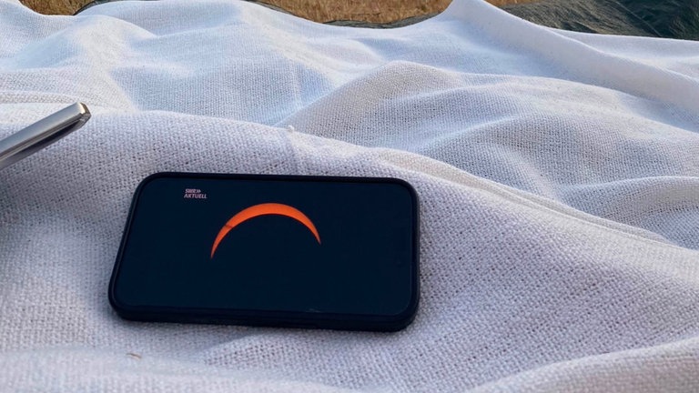 Eine Picknick-Decke liegt auf dem Boden. Darauf ein Tablet, worauf der SWR Aktuell Livestream läuft.