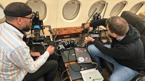 Forschende richten im Flugzeug Kameratechnik ein. Satelliten-absturz tonga stuttgart