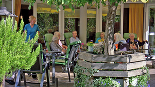 Senioren sitzen auf der Terrasse einer Pflege-WG