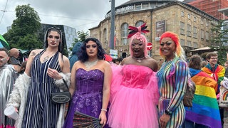 Vier pompös gekleidete Drag-Queens posieren vor der Kamera.