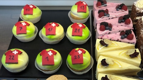 Rote Muffins liegen beim Bäcker im Regal. Das Muster gleicht einem Fußballtrikot.