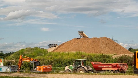 Ein LKW lädt auf einem Erdaushubhügel Erde ab.