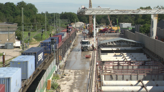 Ein Güterzug fährt an einer Baustelle vorbei.