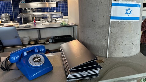 Ein blaues Telefon für Reservierungen, daneben die Flagge Israels: Gastwirt Bilal Aloge setzt klare Botschaften. 