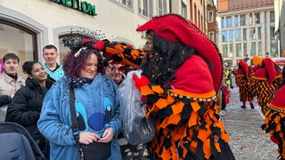 Freiburger Narr reibt Besucherin beim Fasnetmendig-Umzug Konfetti in die Haare
