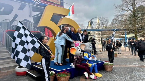 Familie Mack posiert mit den Maskottchen des Europa-Parks vor einer goldenen 50.