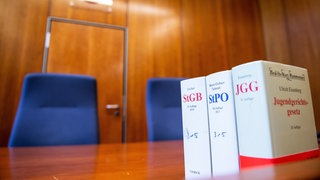 Gesetzesbücher stehen auf einem Tisch im Gerichtssaal