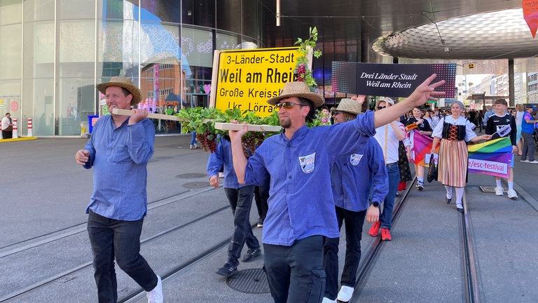 Bei der Eröffnungs-Parade des ESC 2025 in Basel waren auch 500 Menschen aus Südbaden dabei. Wie diese vier Winzer, die das Ortsschild von Weil am Rhein (Kreis Lörrach) in einer Sänfte durch die Stadt trugen.