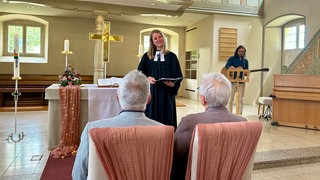 Das Ehepaar Anita und Werner Gerteisen sitzen vor dem Altar der Bergkirche in Opfingen. Vor ihnen steht die Pfarrerin Kristina Lallathin.