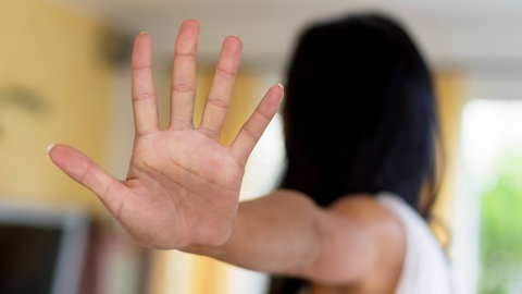 Eine Frau hält die Hand zur Abwehr.