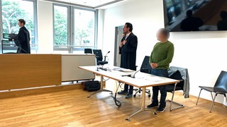 Der Angeklagte steht im Landgericht Freiburg an seinem Platz. Neben ihm sein Verteidiger.
