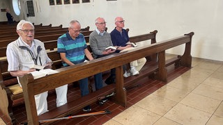Männer sitzen in Kirchenbank
