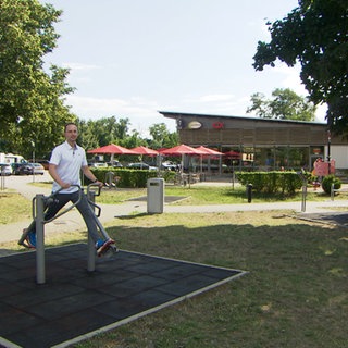 Igor Samsonov, Physiotherapeut aus Freiburg, zeigt an Sportgeräten an einer Raststätte, wie man den Kreislauf wieder in Schwung bringen kann. 