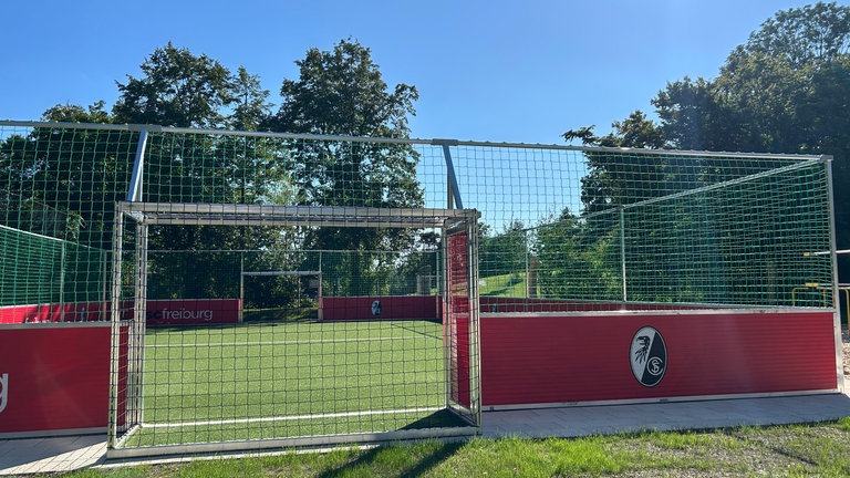 Ein kleines Fußballfeld mit der Aufschrift "SC Freiburg" an der Innen- und Außenbande.