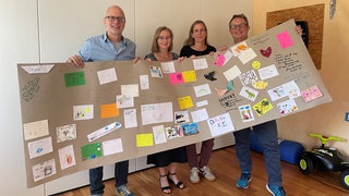 Menschen halten ein Schild hoch. Dabei geht es um Dankesbotschaften für den Erhalt des Autismuszentrums Südbaden.