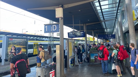 Bahnreisende an Gleis 1 des Freiburger Hauptbahnhofs.
